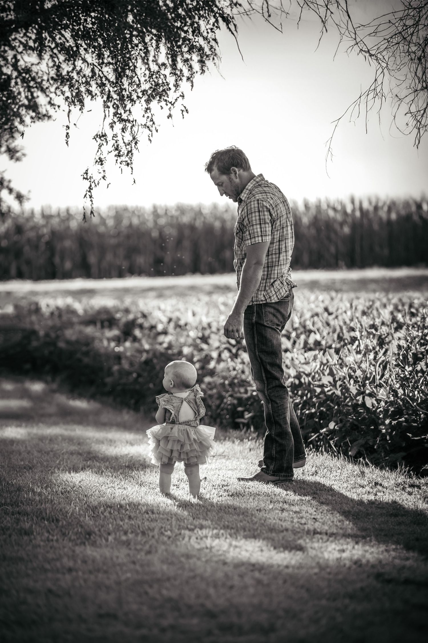 Black and white outdoor series showing two people walking together in a field with soft focus.