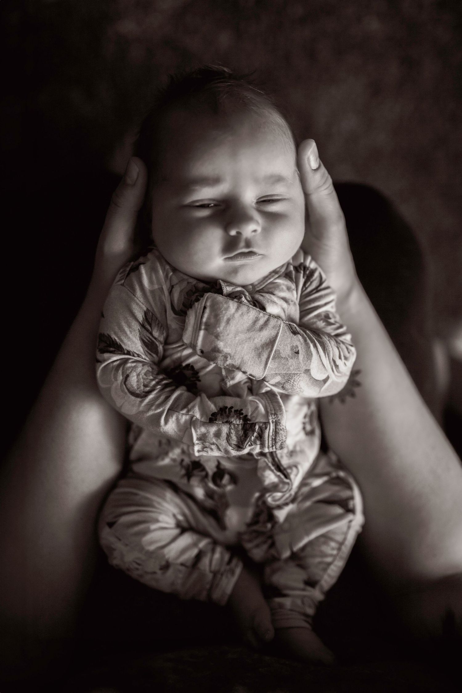 Black and white portrait of a sleeping infant in soft lighting.