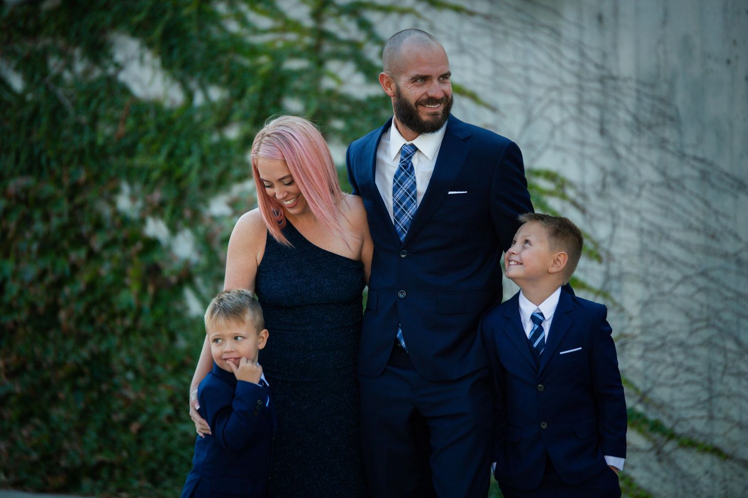 Family of four wearing coordinated navy formal attire poses together outdoors.