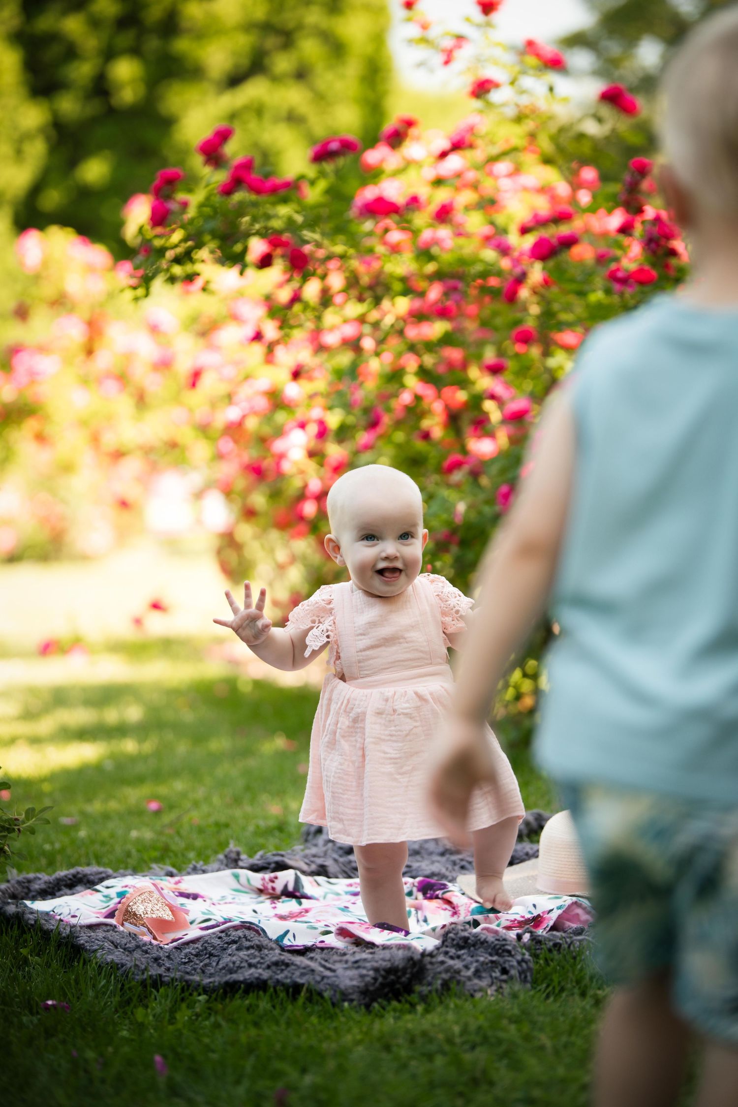Joyful outdoor portrait session captures sweet moments amid blooming pink flowers and lush greenery.