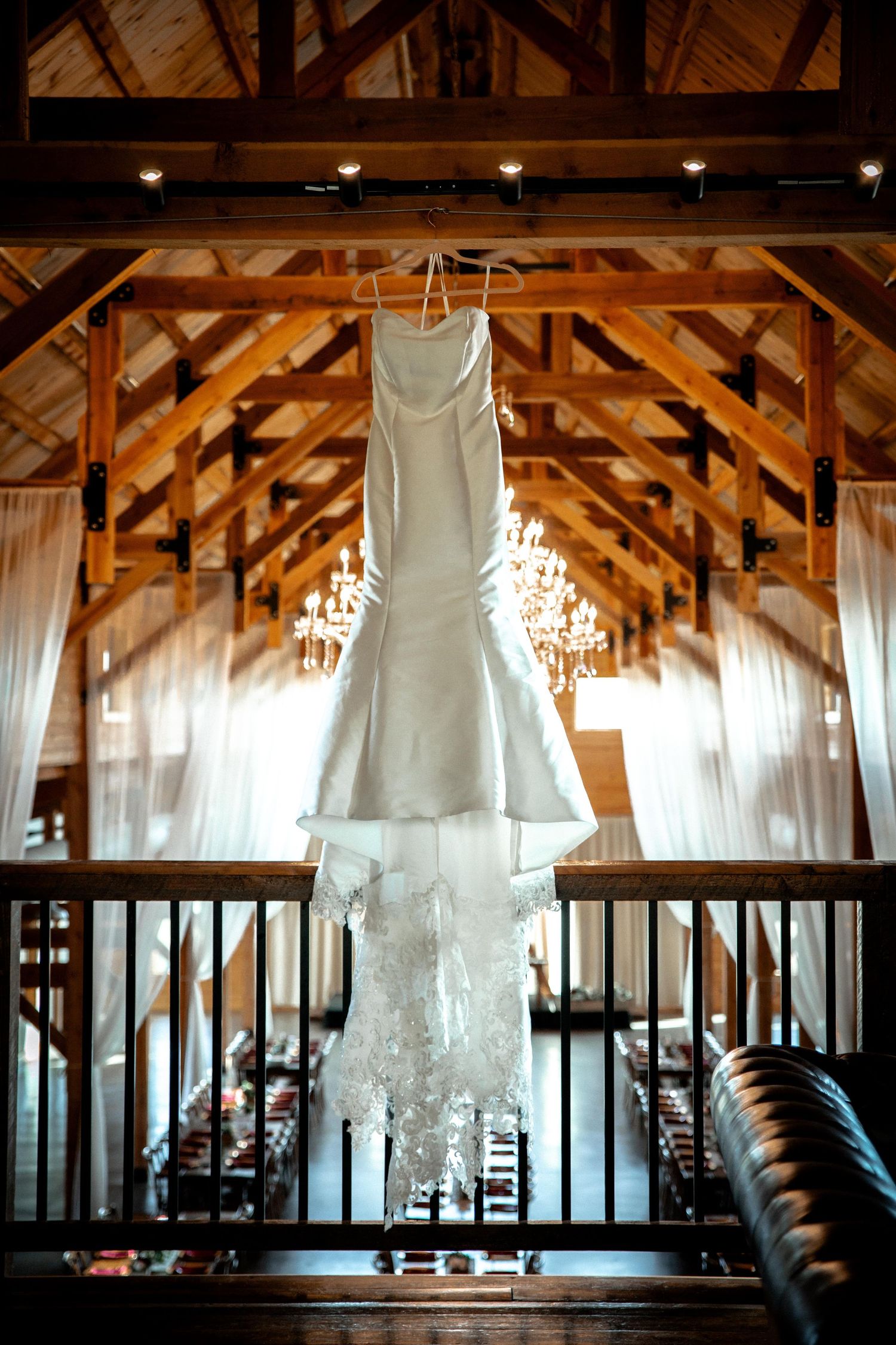 Rustic barn wedding venue interior with exposed wooden beams and hanging white decor.