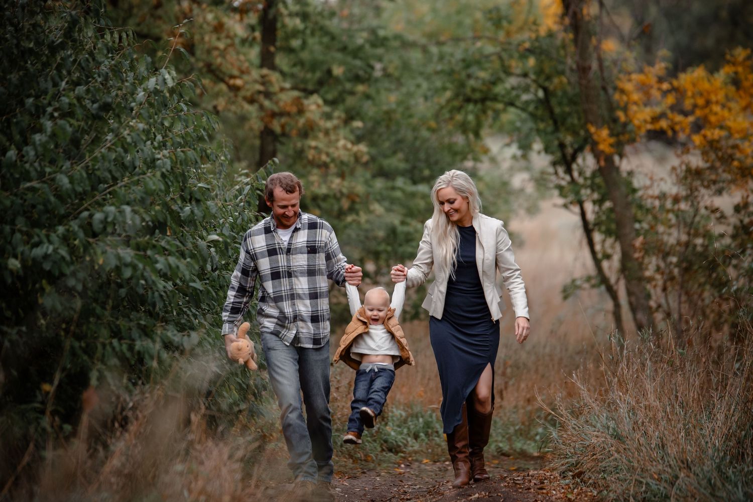 Family walking together through autumn trees on nature trail. Photographer in Sioux Falls, SD