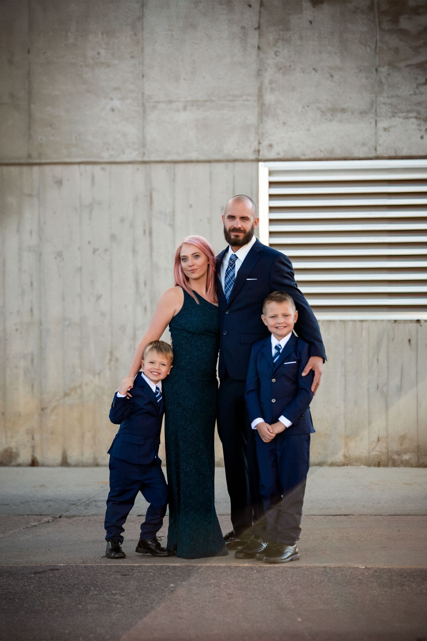 A collection of family portraits showing parents and child in navy blue outfits against a concrete wall background.
