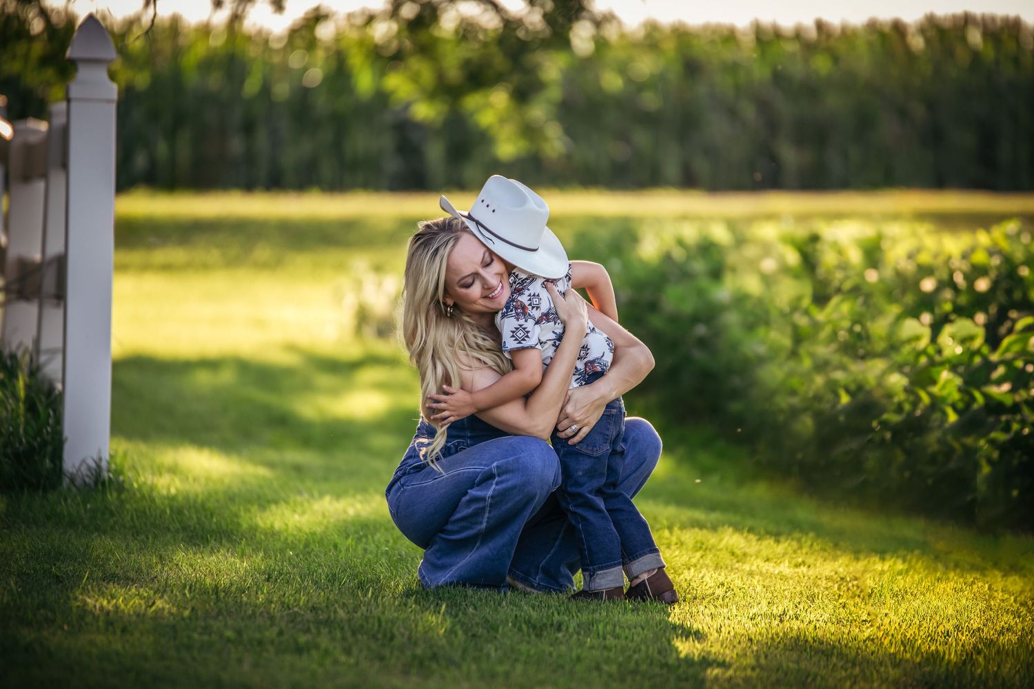 Mother and child sharing tender moment on grass during golden hour.