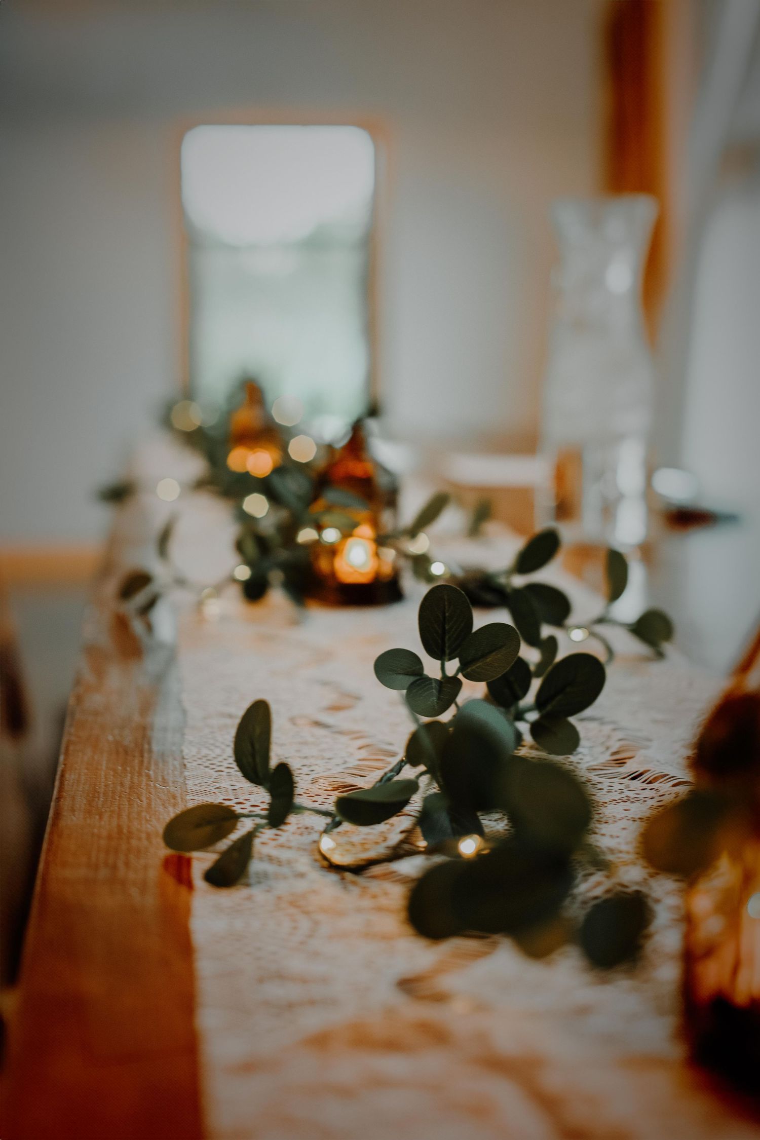 Elegant table decor with eucalyptus leaves and candles creating a romantic atmosphere.