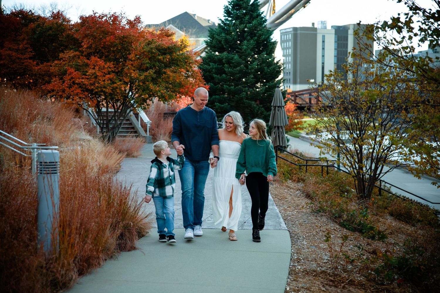People walking along a scenic autumn path with colorful fall foliage and trees in the background.