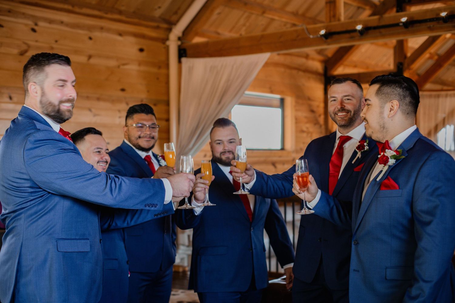 Groomsmen in navy suits celebrate during a wedding reception.