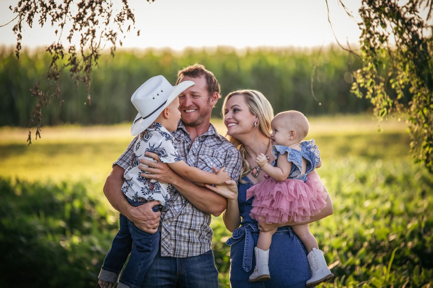Family sharing joyful moment together at sunset in front of cornfield.
