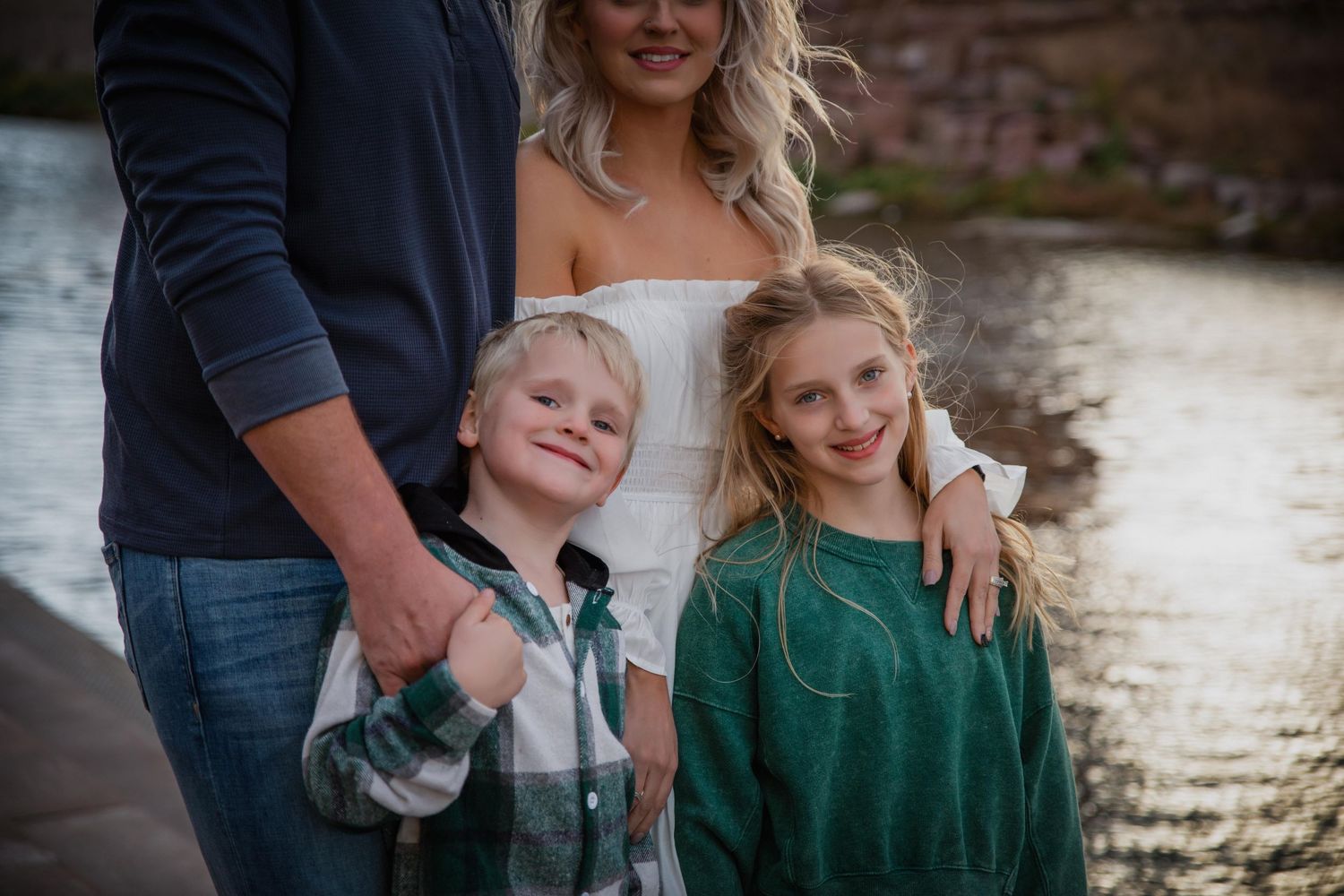Family enjoying a tender moment together outdoors during a sunset photo session by the water.