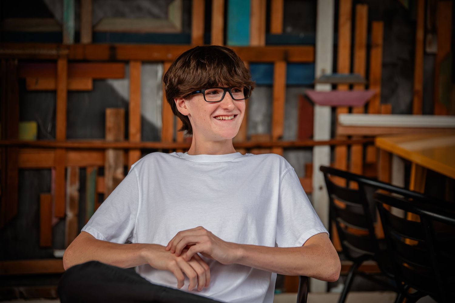Indoor portrait of student in white t-shirt sitting at table. Photographer in Sioux Falls, SD
