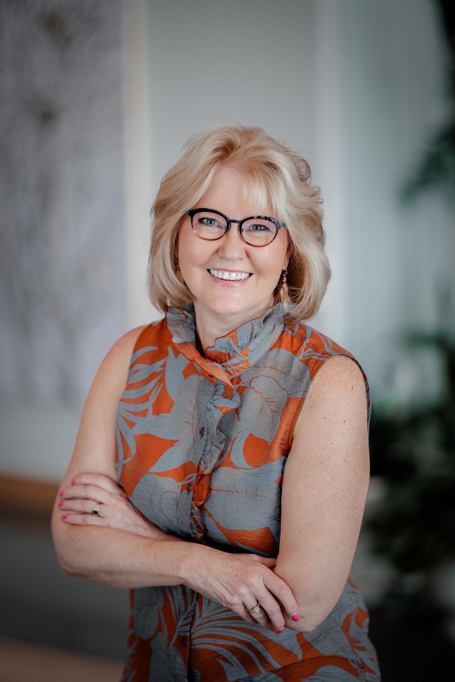 Professional headshots featuring an orange and gray patterned scarf and glasses indoors.