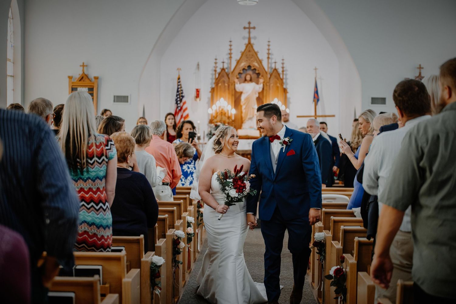Traditional church ceremony with wooden pews and golden altar decorations. Photographer in Sioux Falls, SD