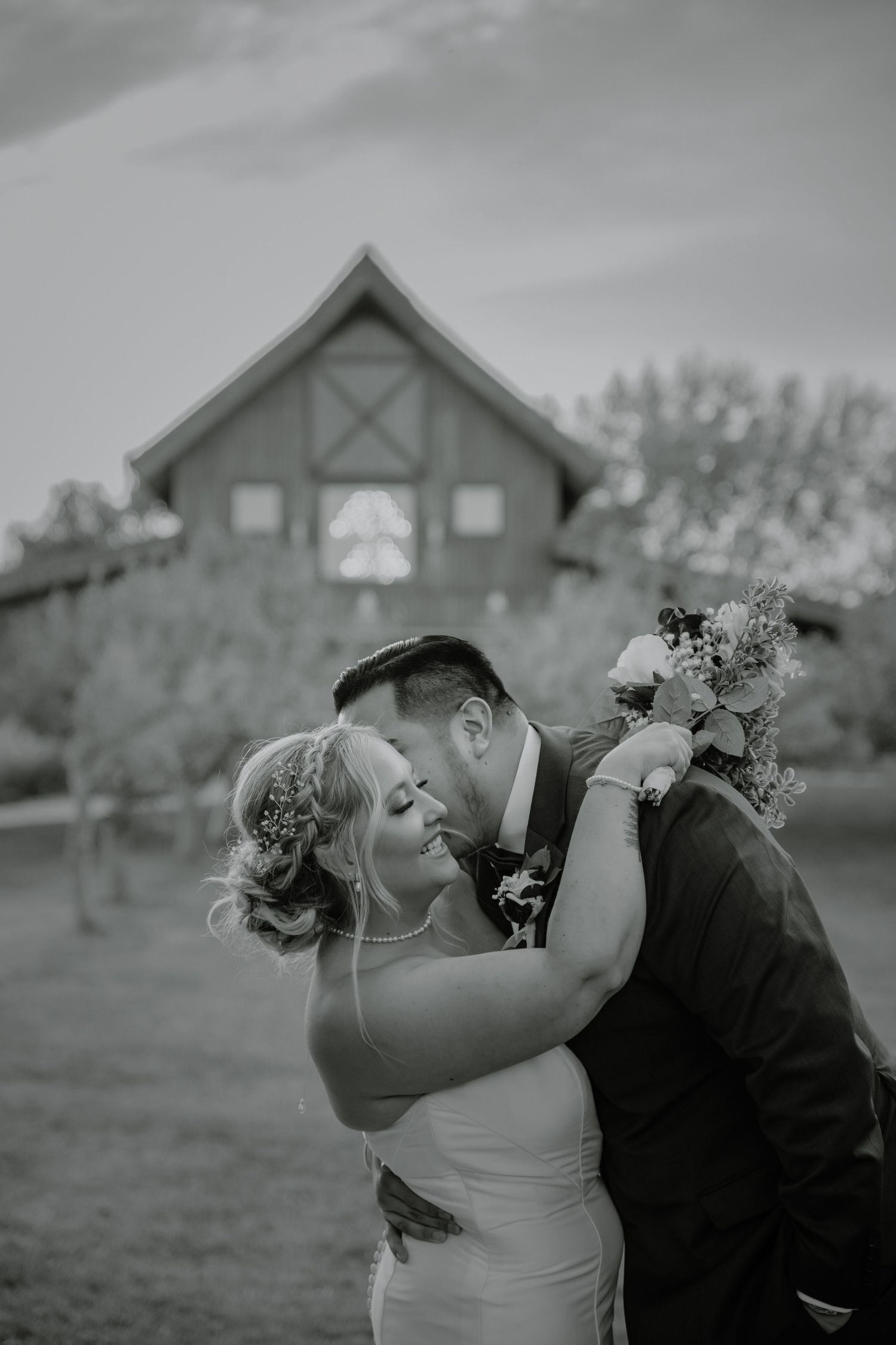 Intimate black and white wedding portrait with rustic barn venue setting.