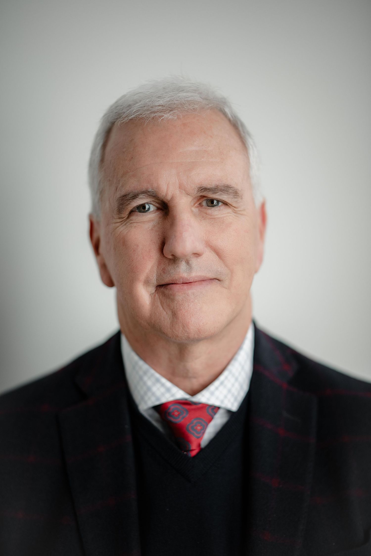 A series of black and white portraits showing someone in a black suit and red tie with different facial expressions.