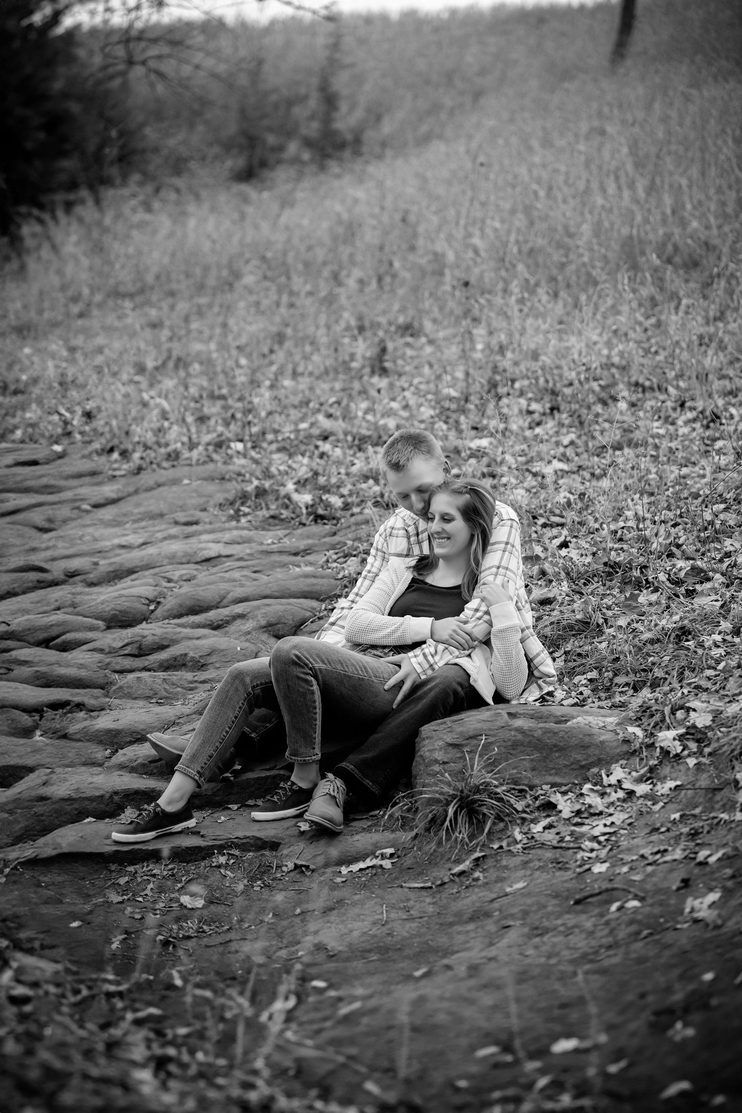 Couple lying together on stone surface in black and white photograph.