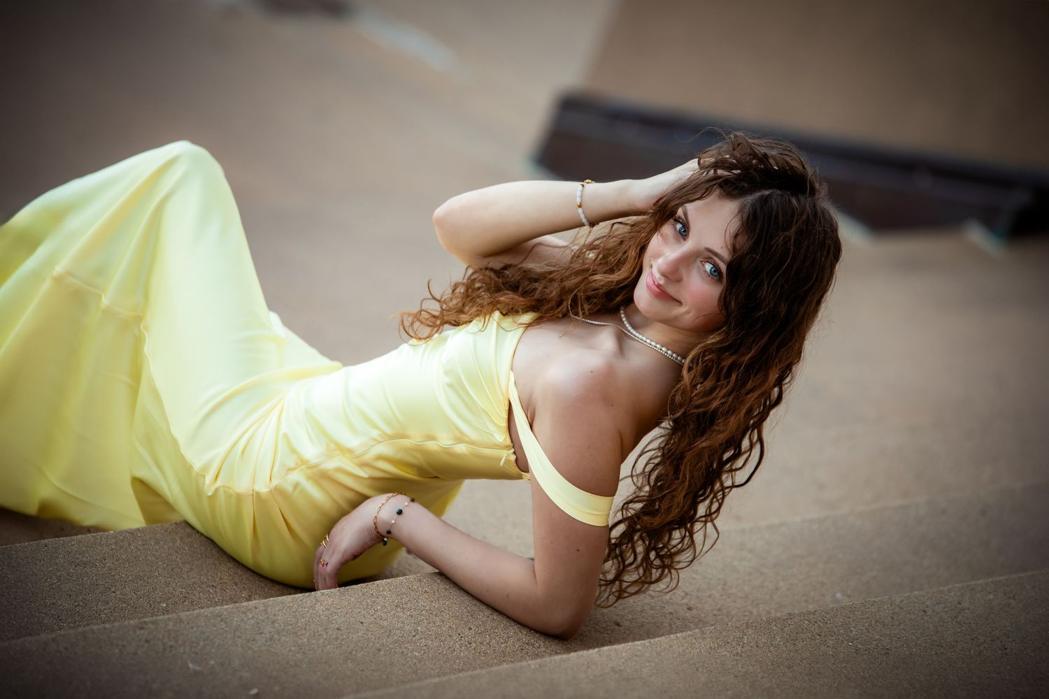 Person in yellow dress lying on floor in artistic boudoir photo session with dark vignette effect.