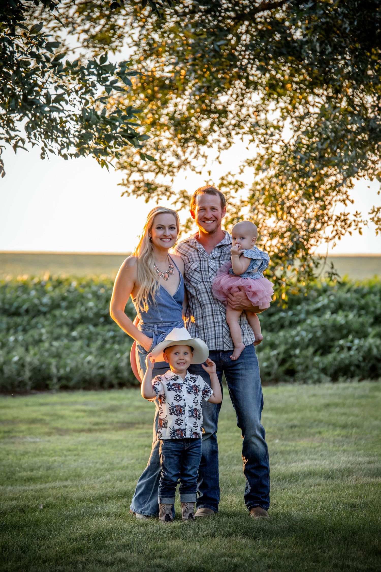 Family walking together under tree branches during golden hour photography session.