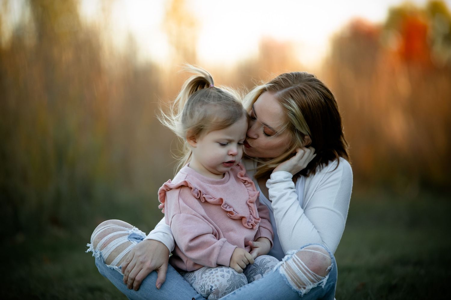 Mother and baby sharing tender moments outdoors during golden hour sunset. Photographer in Sioux Falls, SD