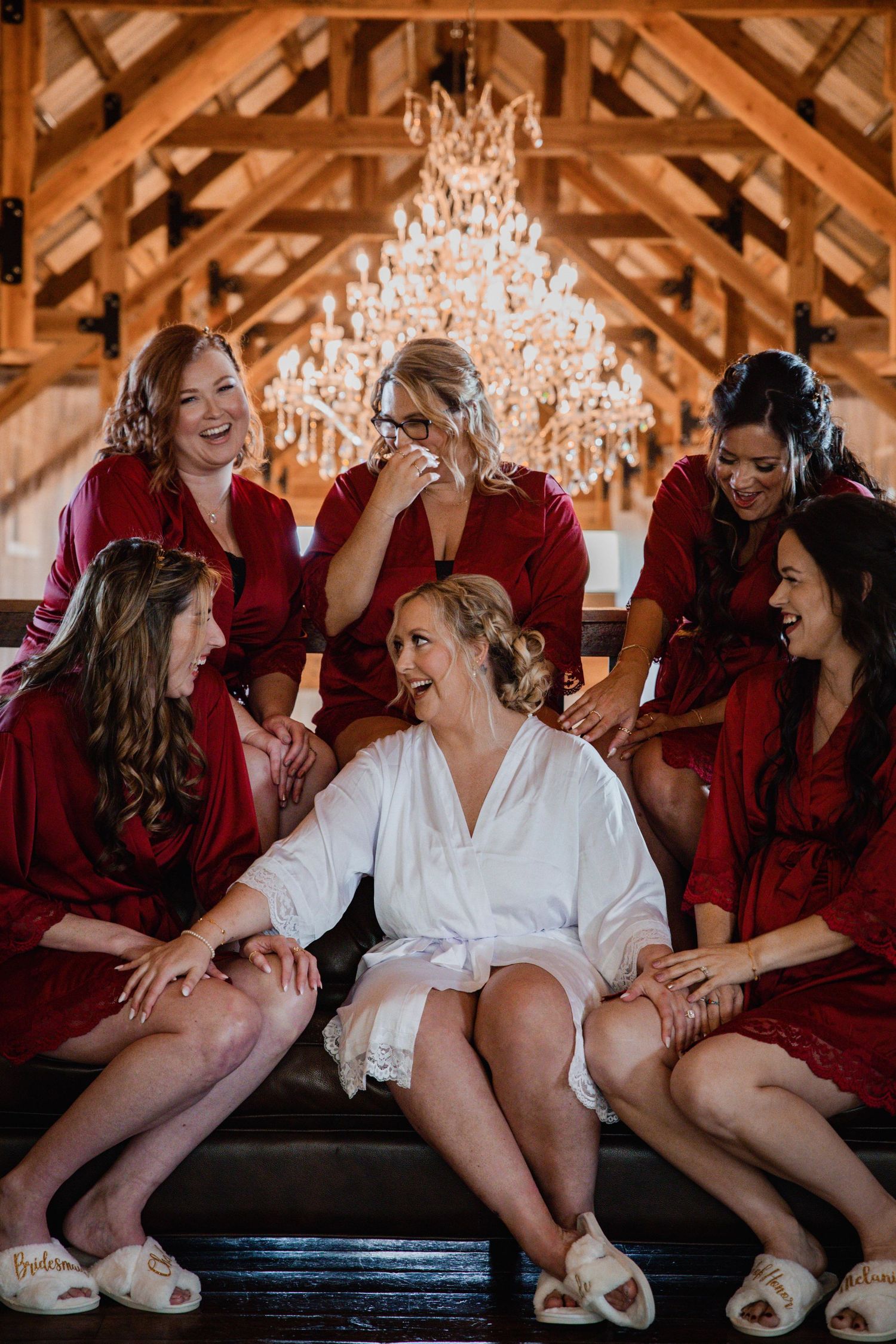 Wedding party in burgundy robes sharing candid laughs during preparation.