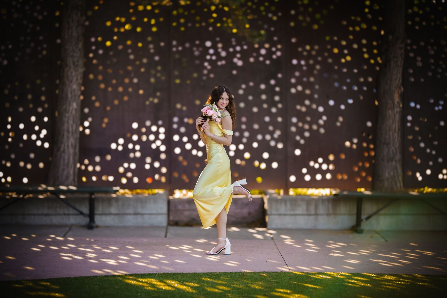 A person in a yellow dress dances gracefully in a park at night surrounded by magical light patterns on the ground.
