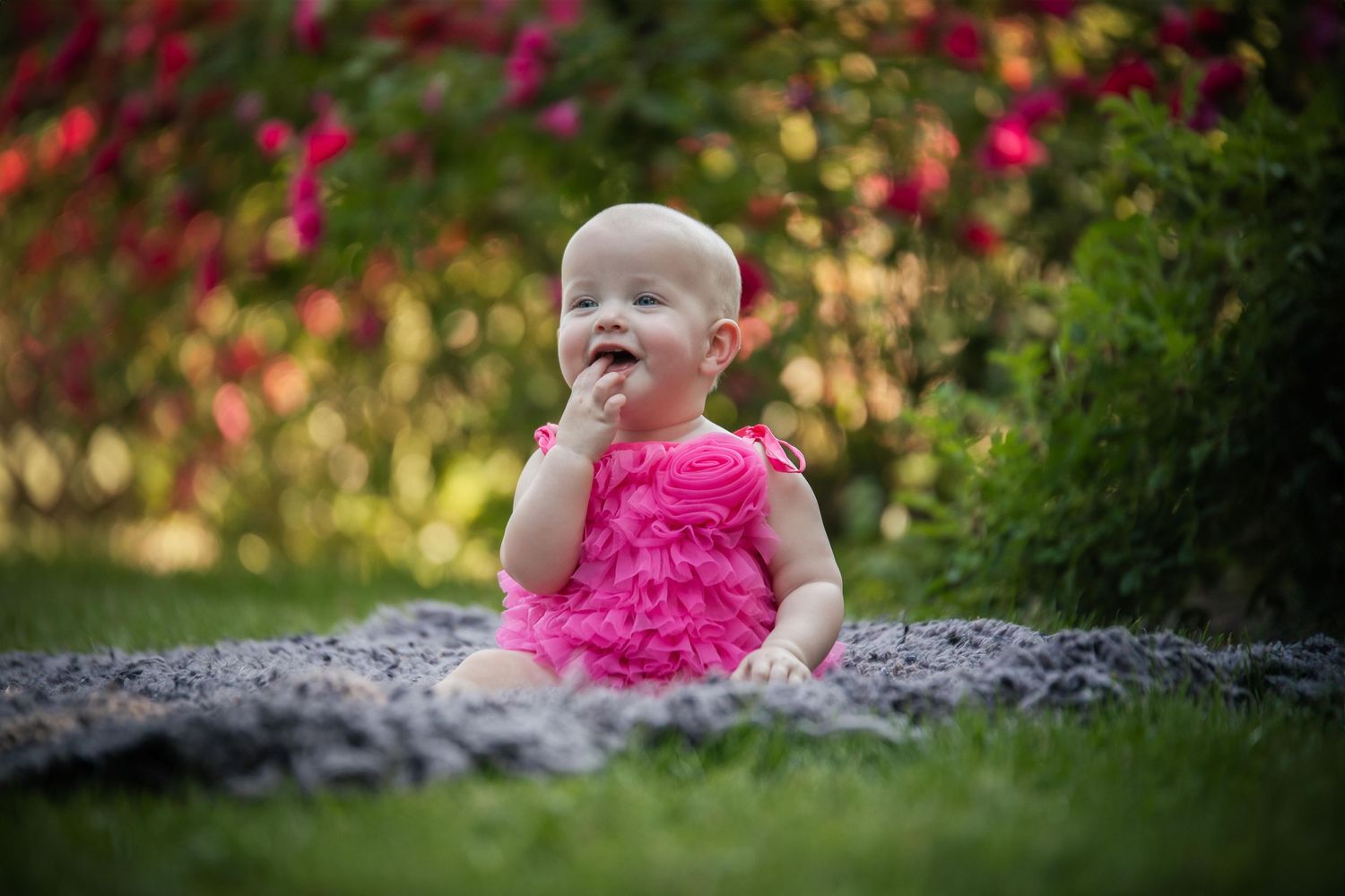 Pink ruffled dress stands out against vibrant garden backdrop during summer photo session.