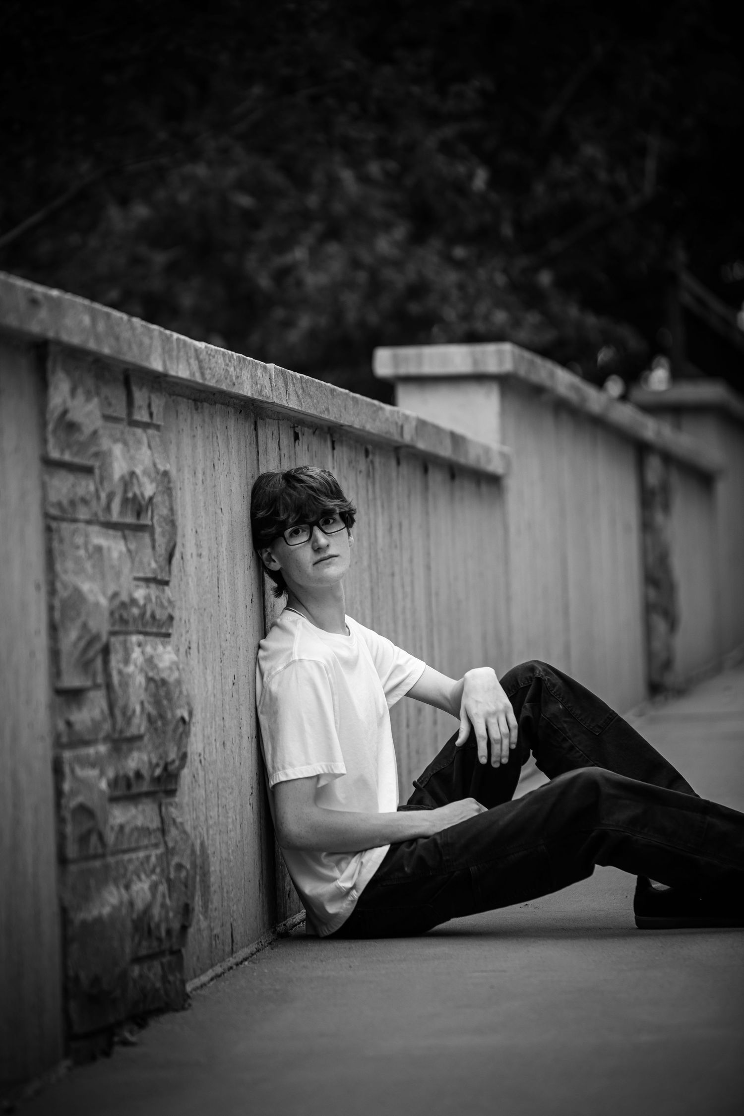 Black and white photo of someone reclining against a stone wall outdoors. Photographer in Sioux Falls, SD