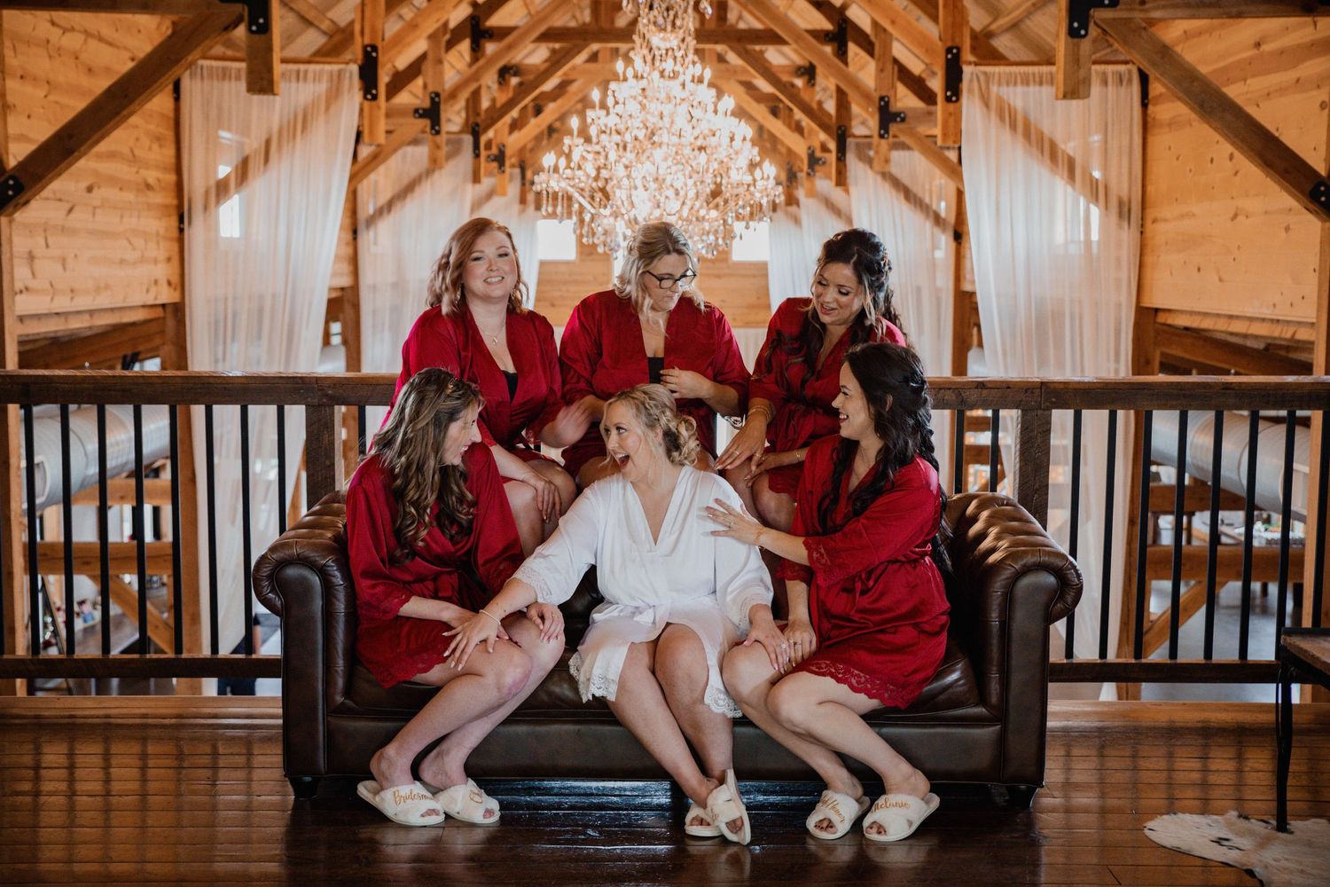 Group photo in rustic barn venue with wooden beams and chandelier.