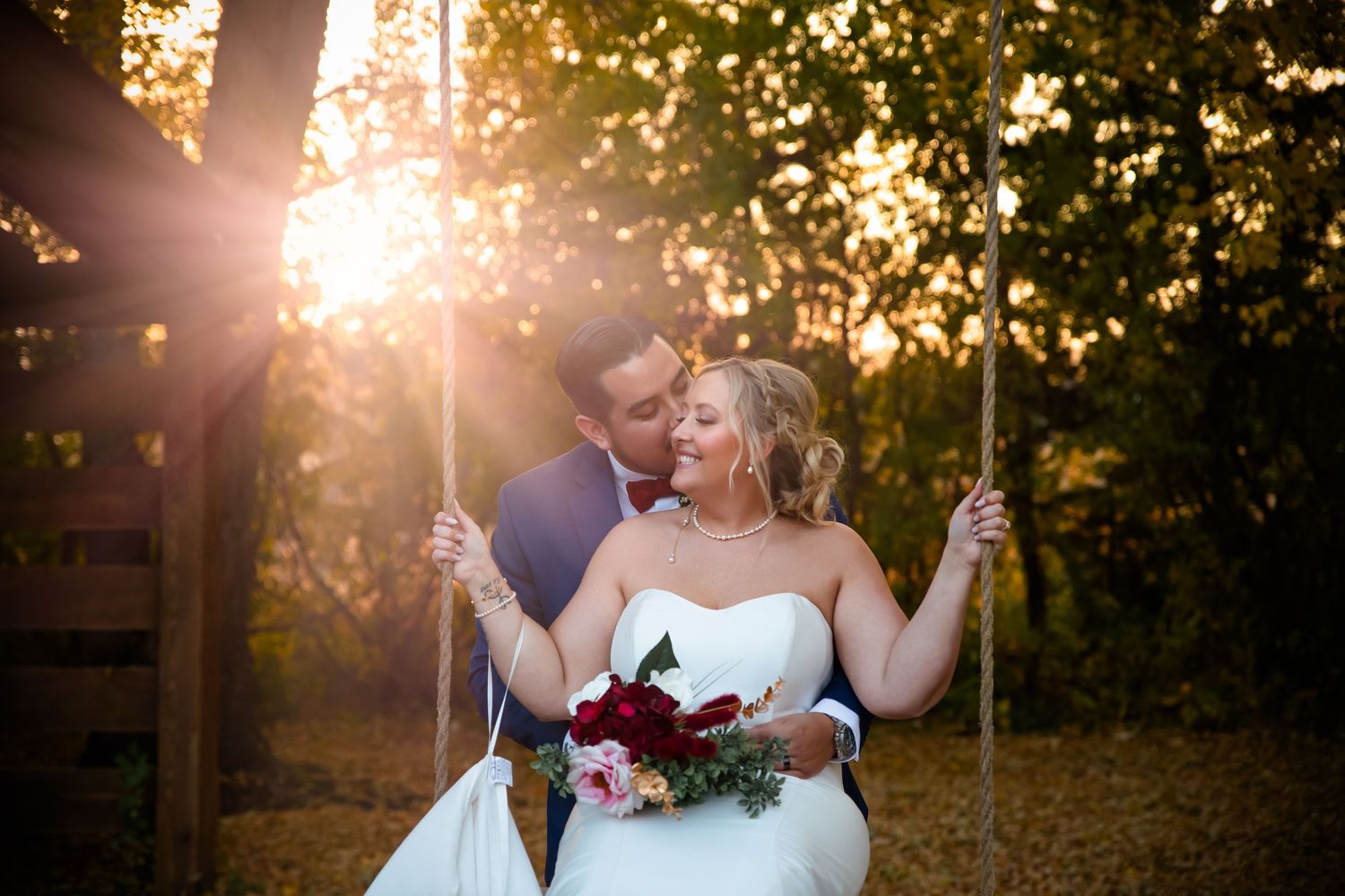 Bride and groom share a romantic moment in a garden at sunset with golden sunlight streaming through the trees.