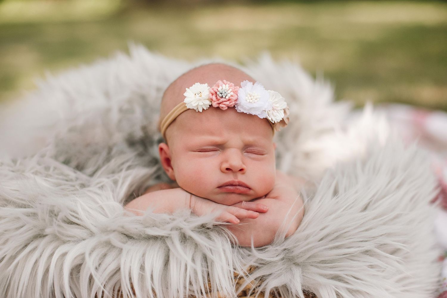 Peaceful newborn baby sleeping on fluffy gray blanket.