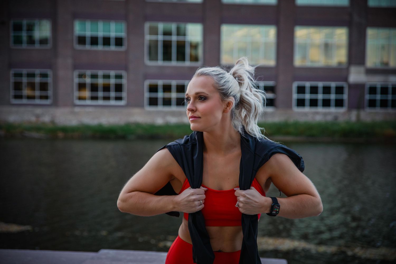 Person exercising in red athletic wear demonstrates stretching movements outdoors.
