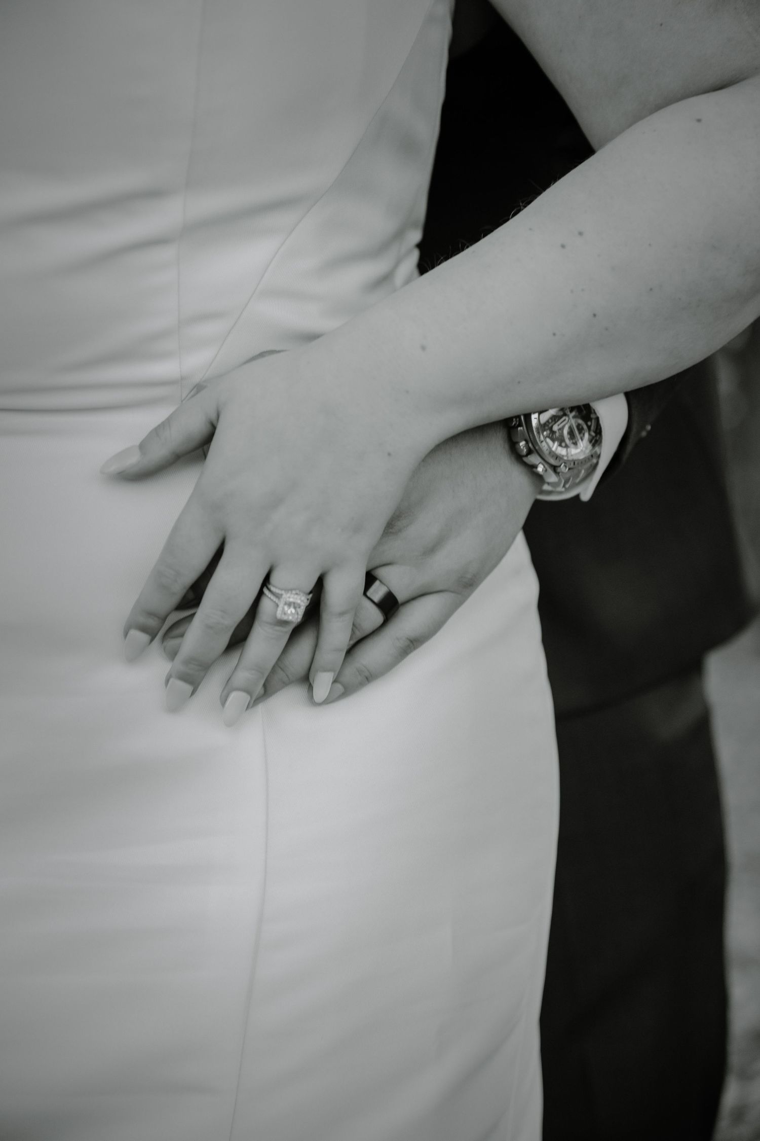 Close-up detail shot of white wedding dress and jewelry in black and white.