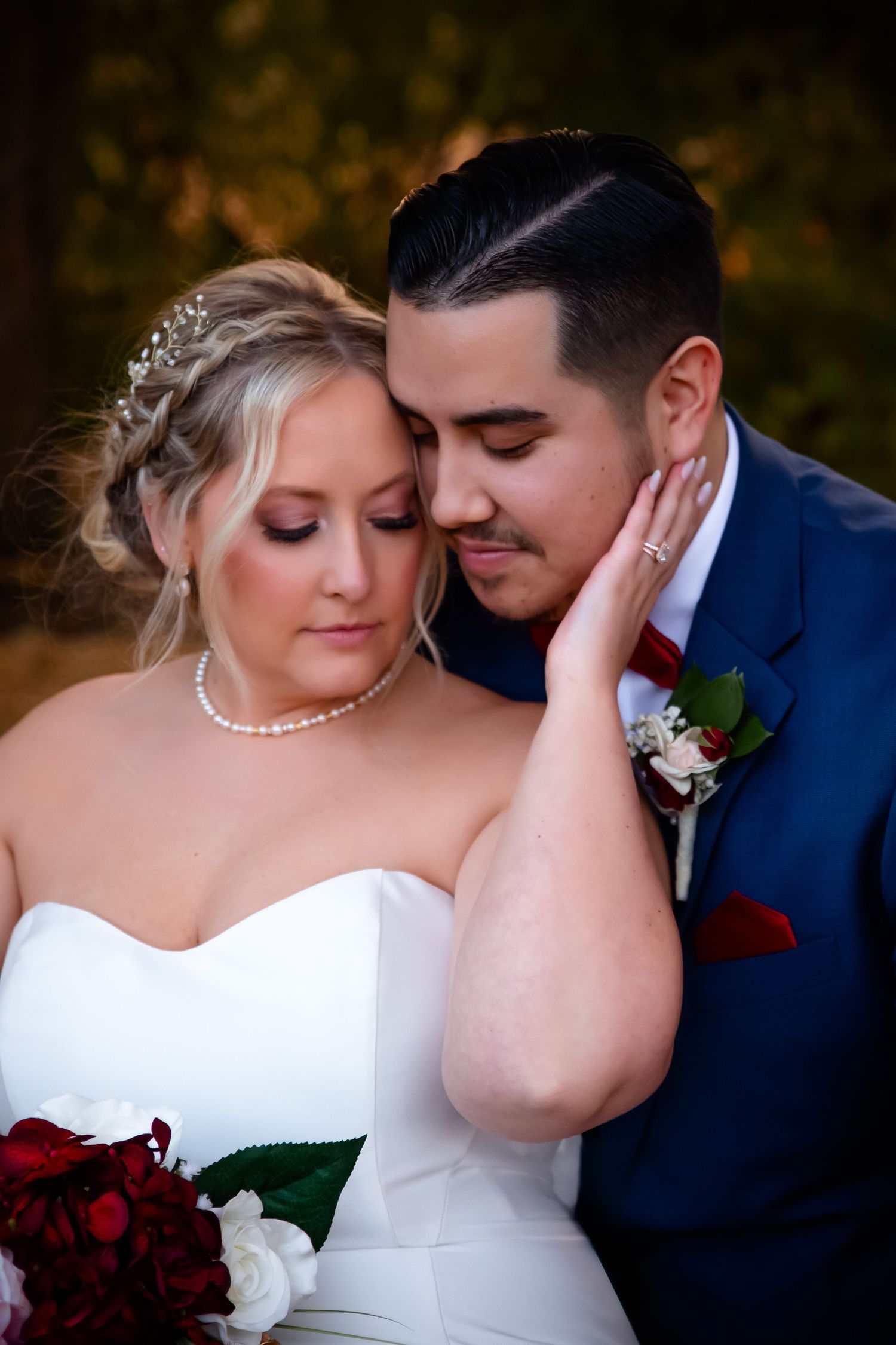 A romantic wedding portrait shows a couple in intimate embrace with the bride in white and groom in navy blue.