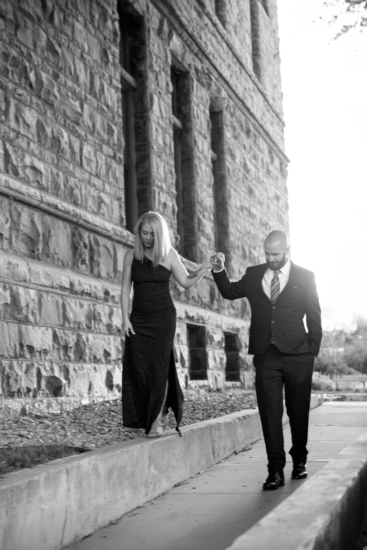 A sequence of black and white photos showing someone walking along a stone building wall.