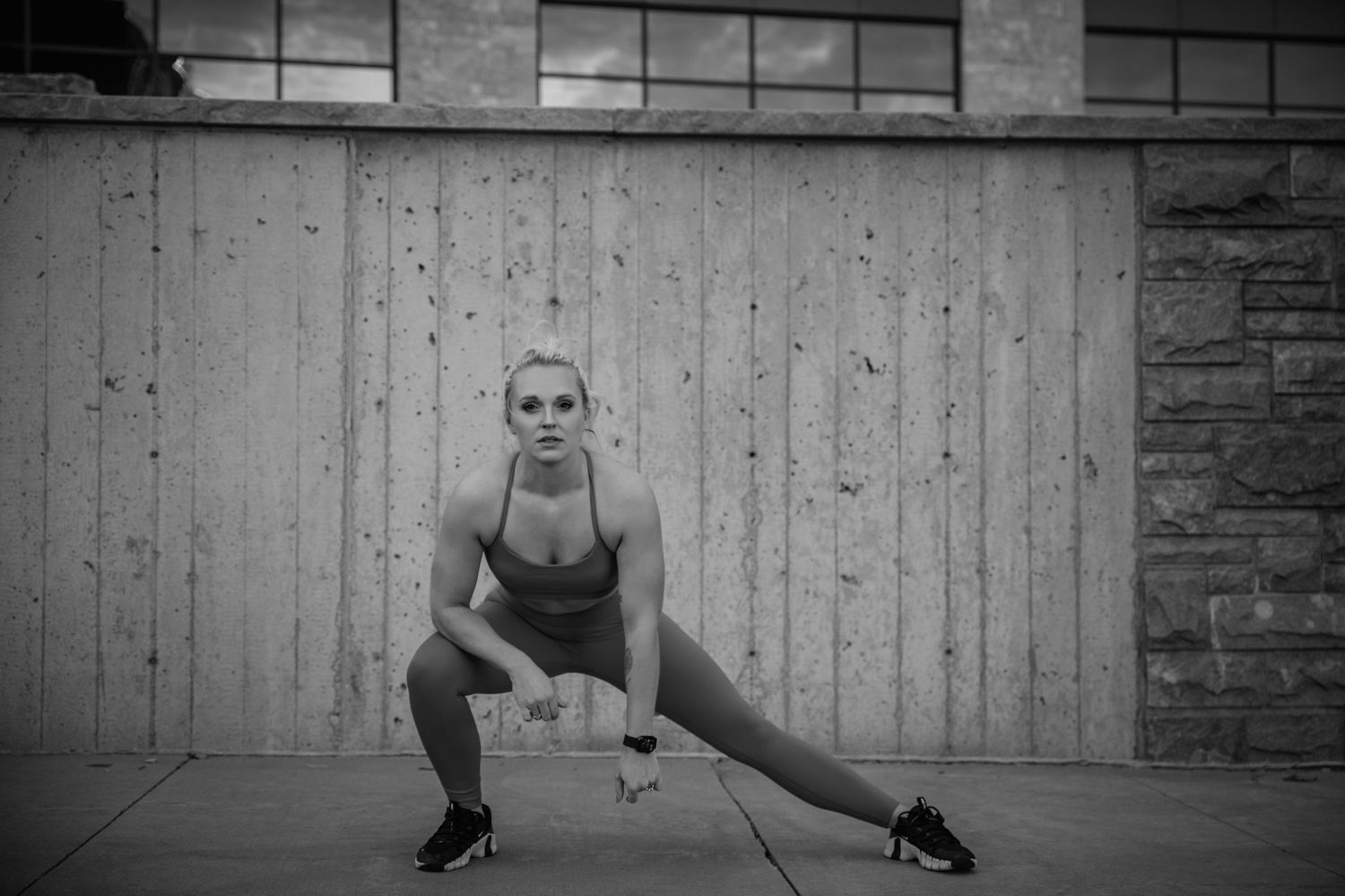 A dancer in athletic wear strikes a dramatic pose on the floor in front of a gray wall.