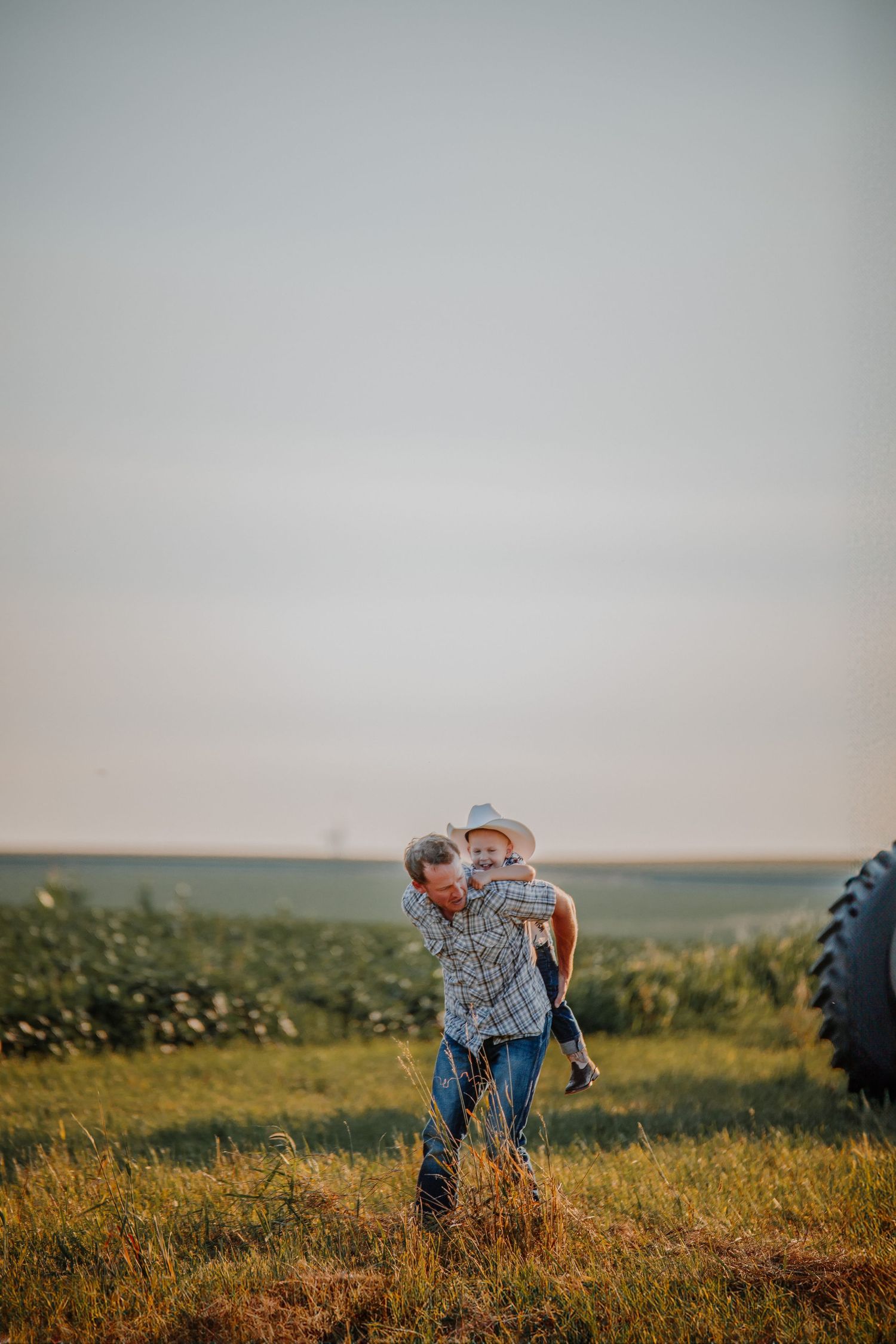 People gather in a rural field during sunset with rolling hills in the background.