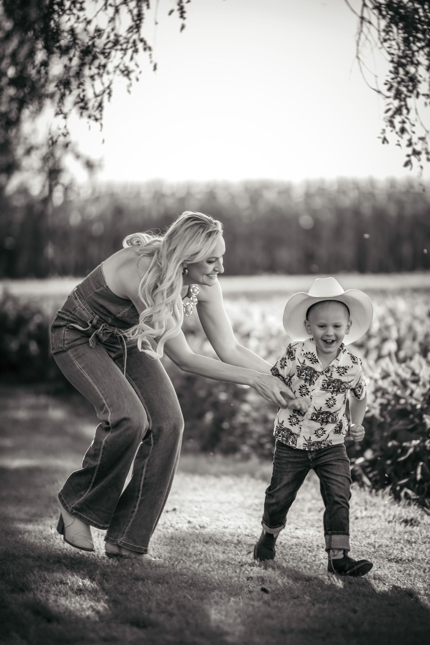 Mother and child playing together outdoors in black and white photography.