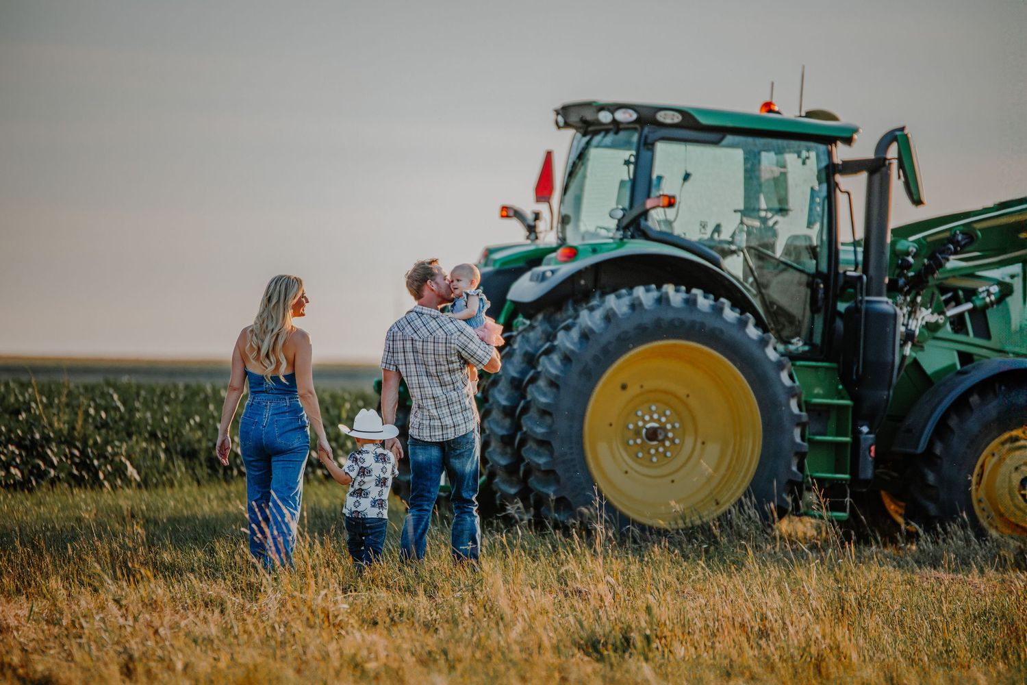 Large agricultural tractors lined up in a grassy field at dusk.