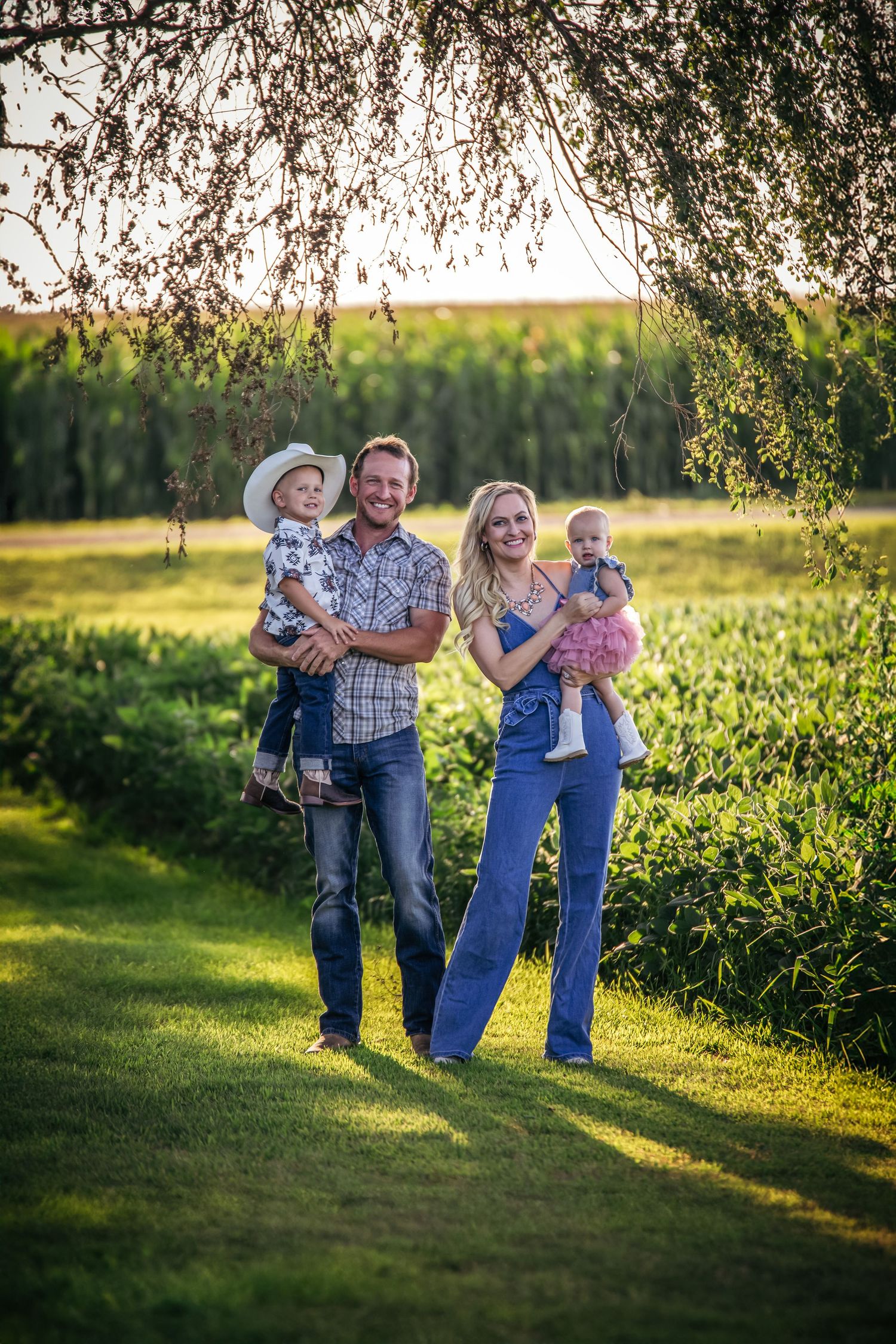 Family enjoying a playful moment together in a sun-drenched field during golden hour.