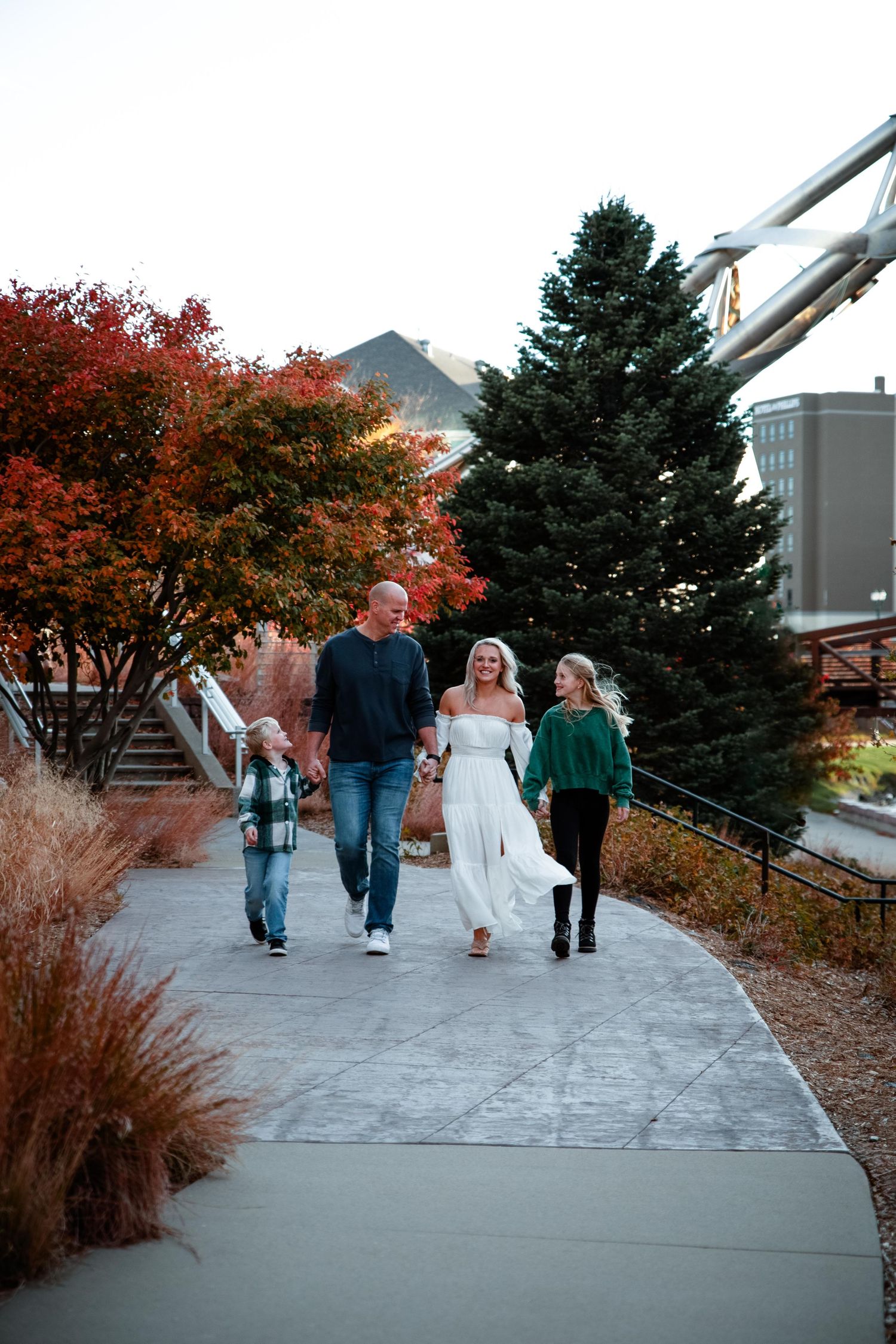 A group of people walking together on a concrete path surrounded by autumn foliage and evergreen trees.