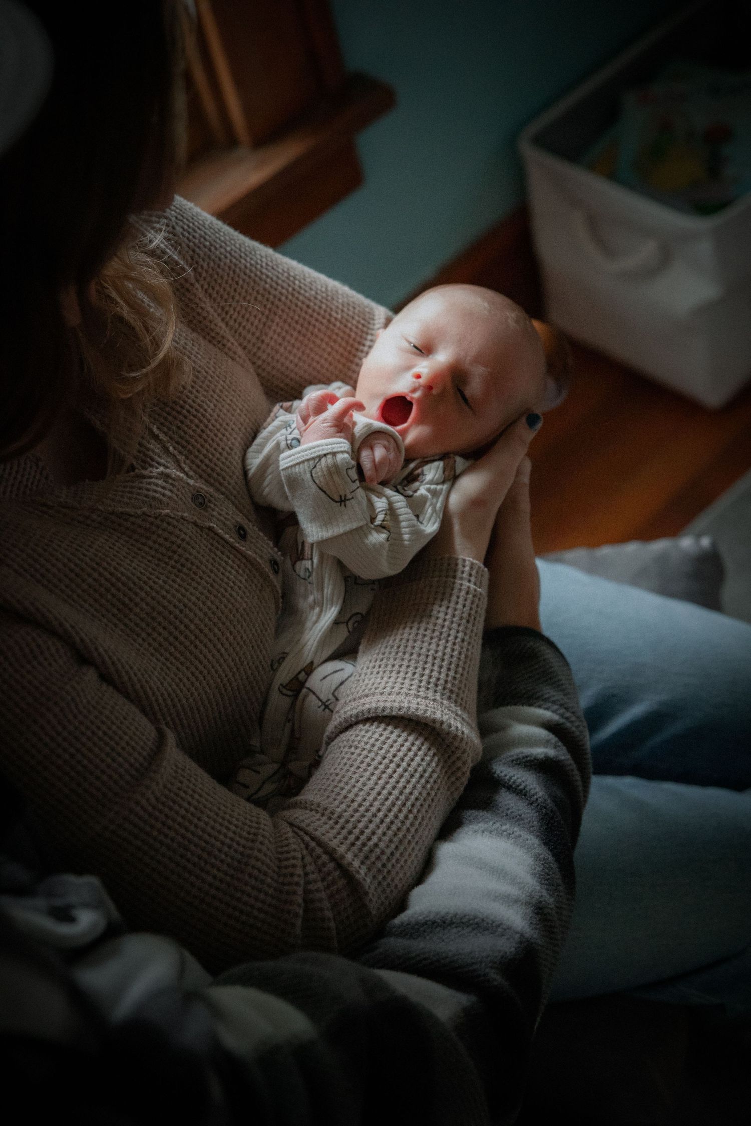 Hands gently hold a soft knitted blanket in a dimly lit room creating a cozy atmosphere.