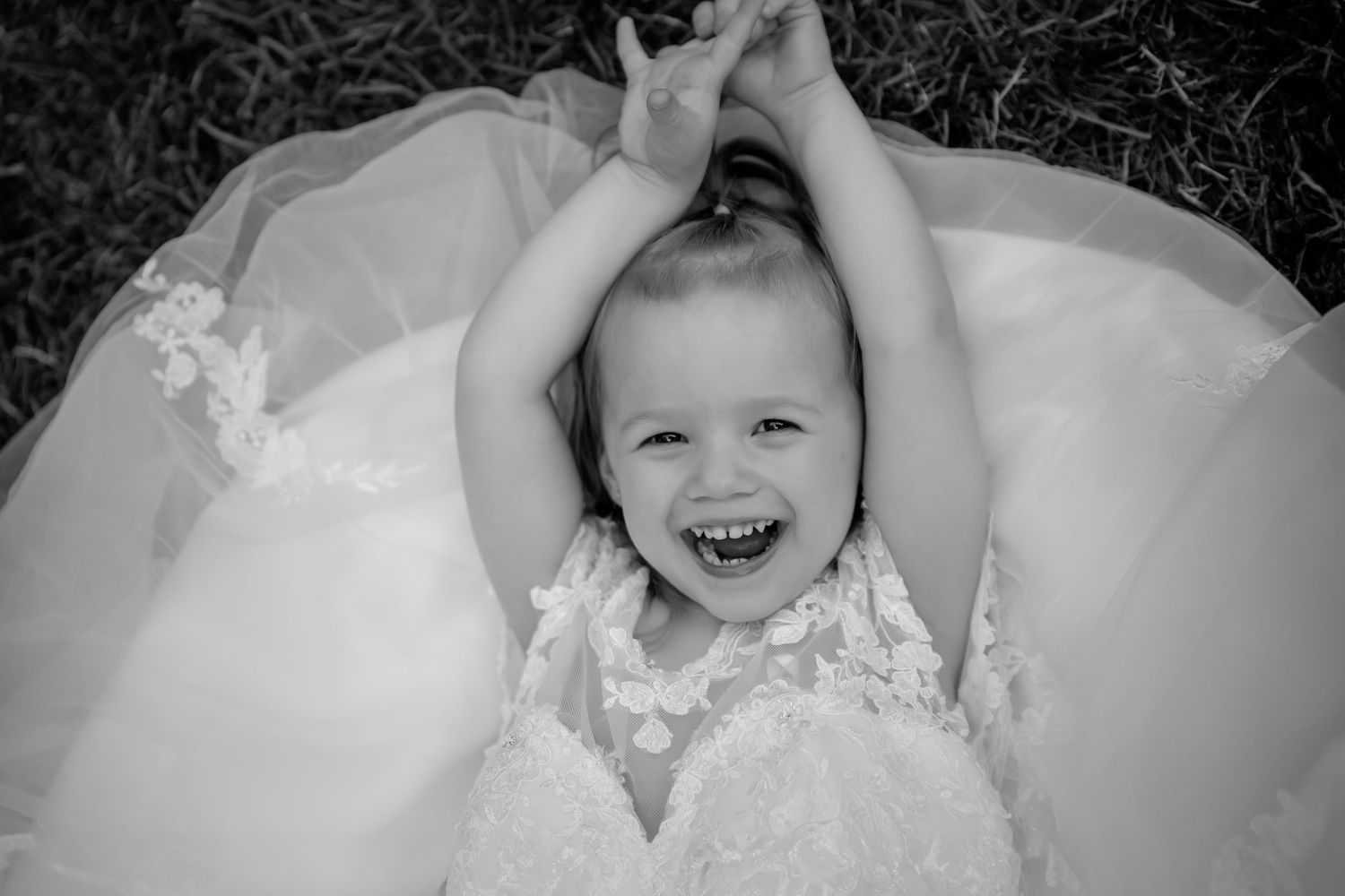 A collage of seven black and white photographs showing a baby in formal white dress against a neutral background.