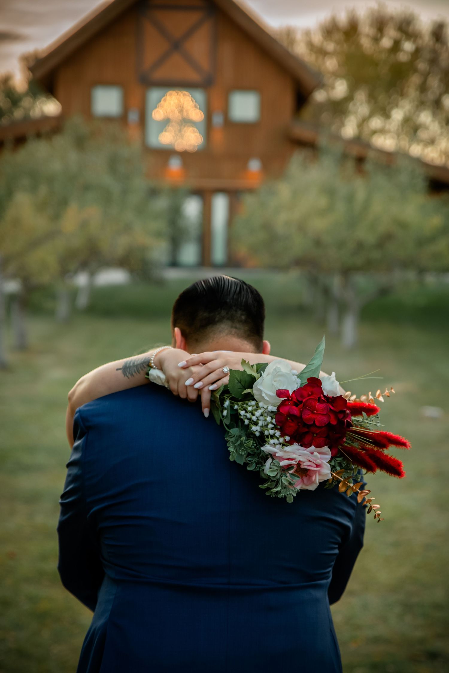 A romantic embrace with red roses against a rustic cabin backdrop during golden hour.