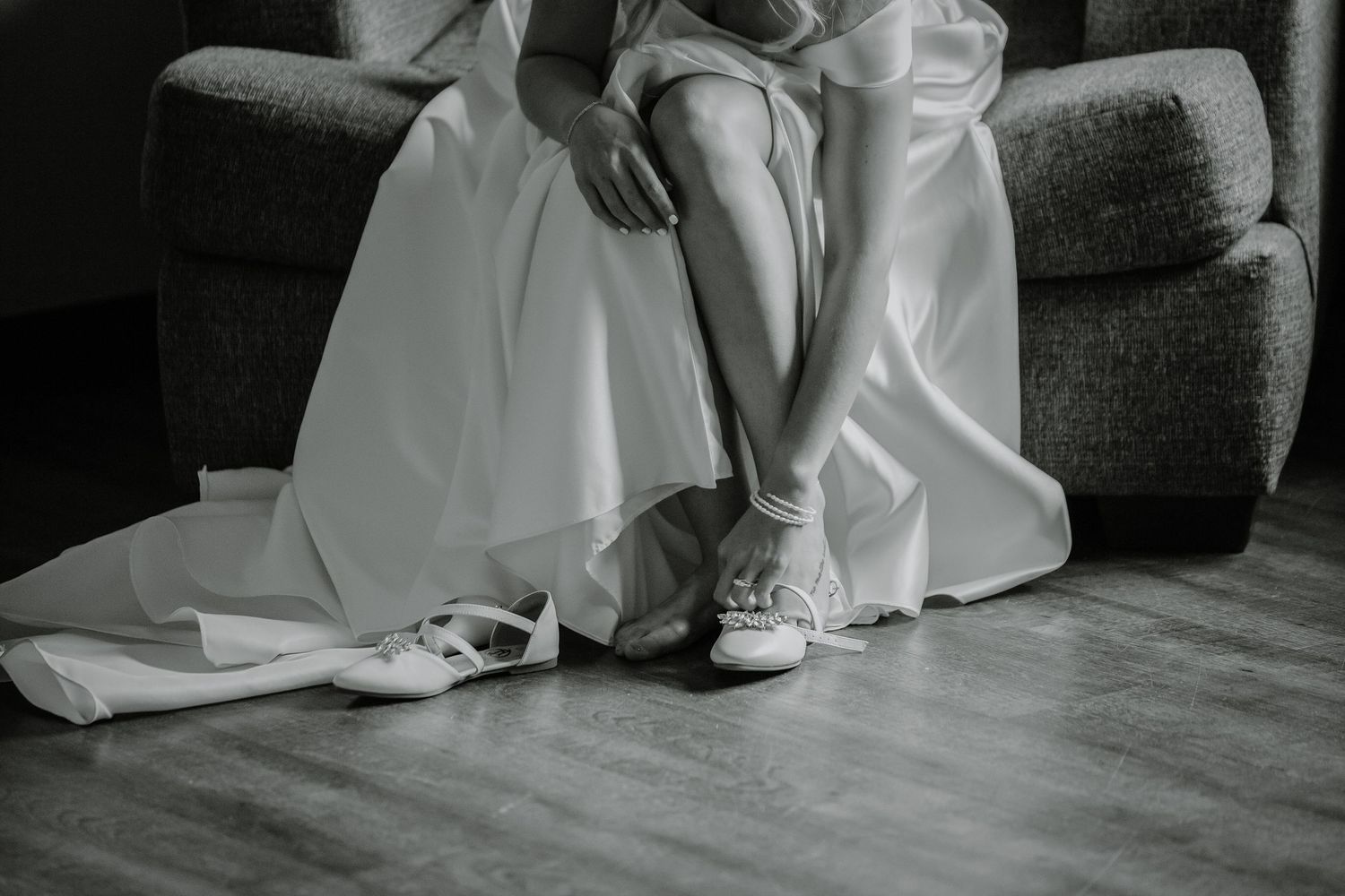 Elegant wedding dress details from the bottom shown against a dark floor.