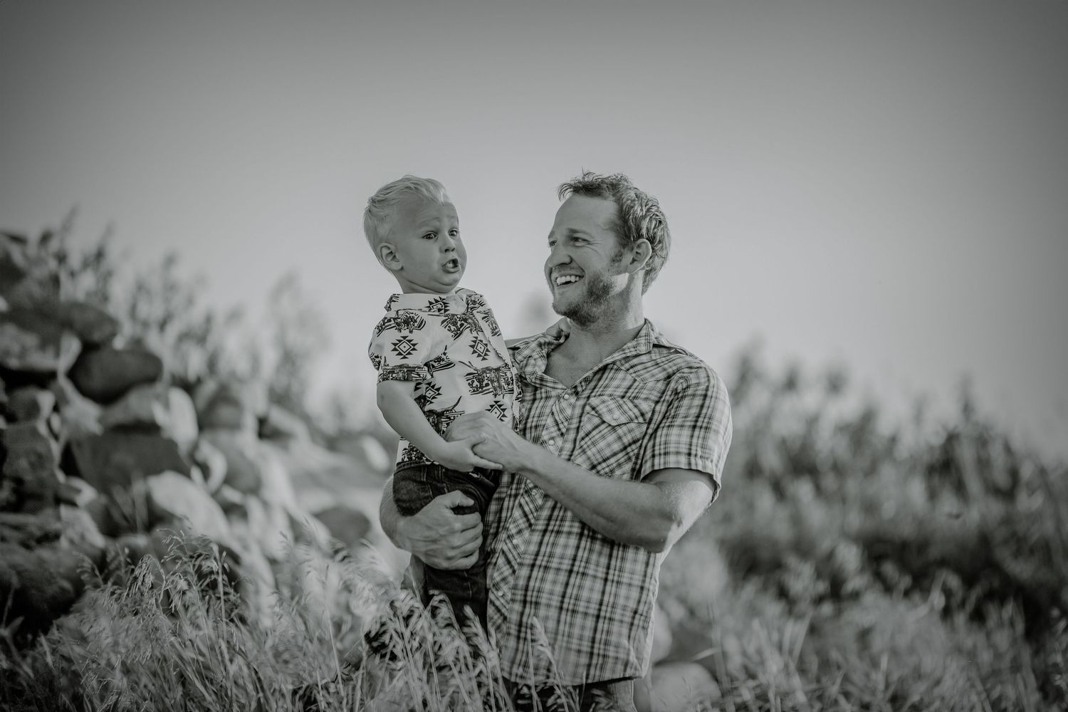 Black and white portrait of family moments in a rural field setting.