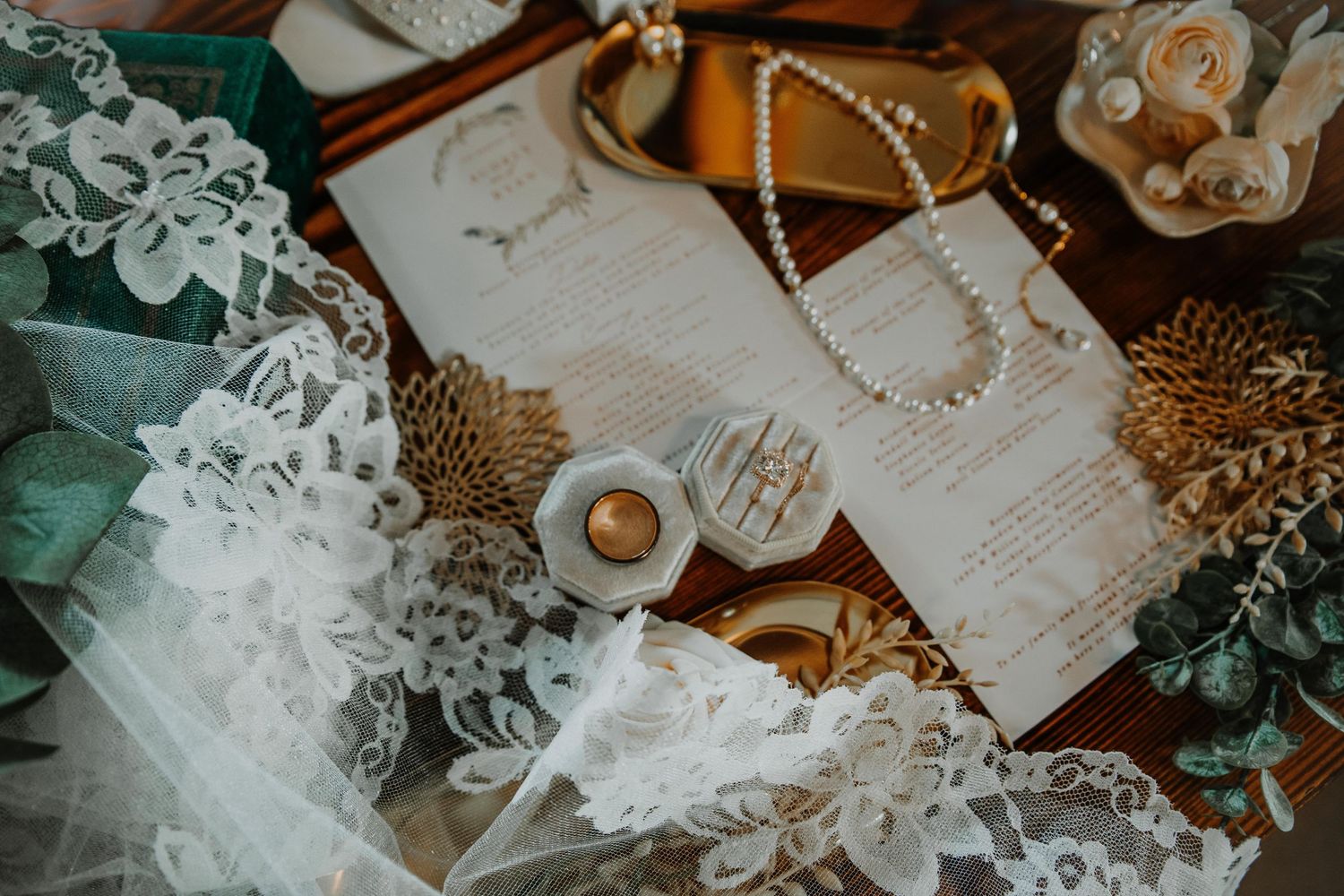 Wedding details including lace trim and pearls artfully arranged on a wooden surface.