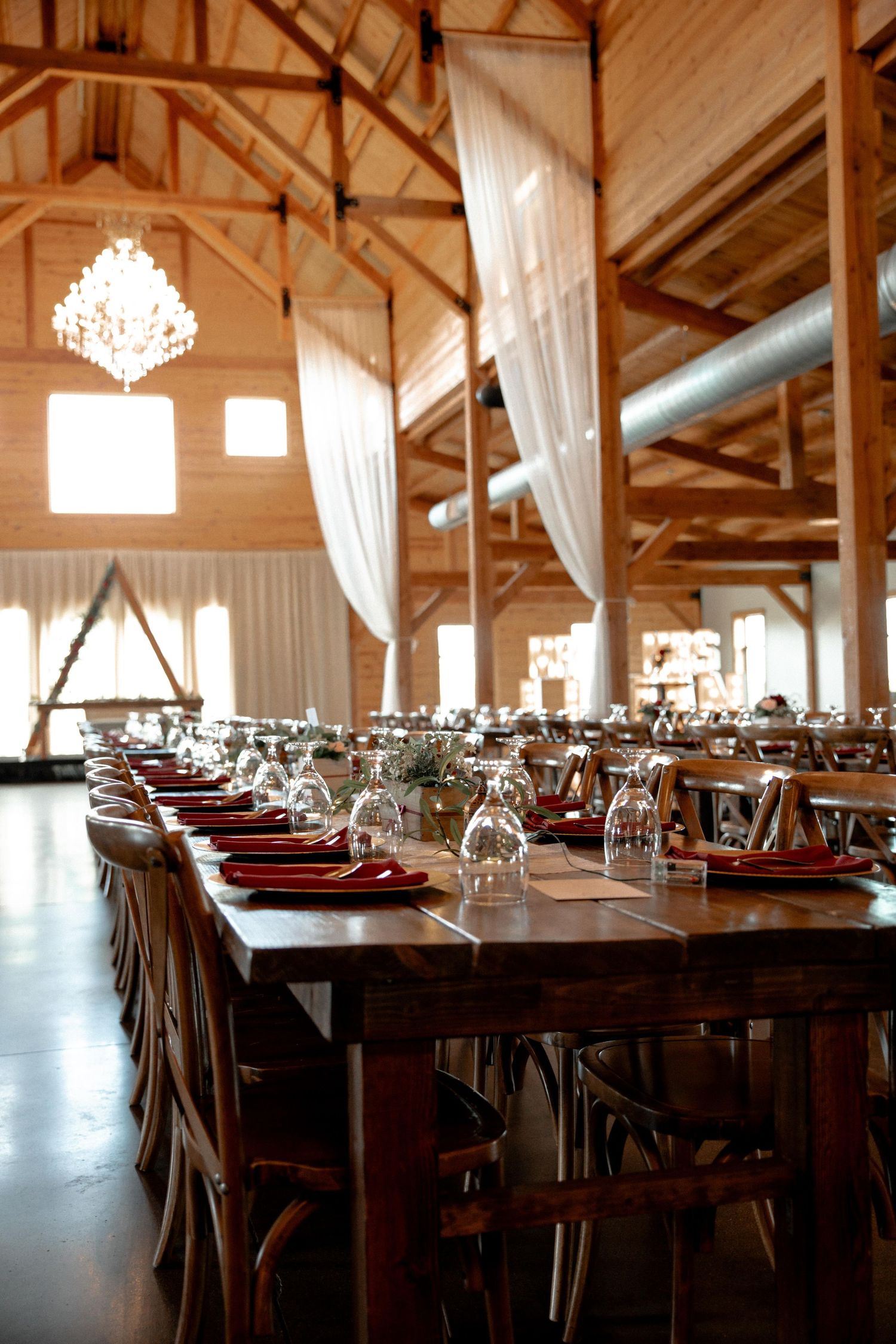 Rustic barn wedding reception with elegant table settings and warm wooden details. Photographer in Sioux Falls, SD