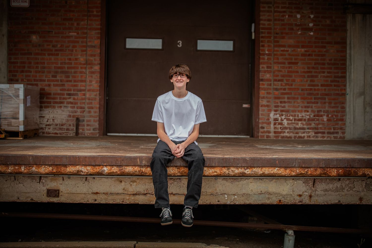 Person sitting on concrete steps in front of brick building wearing casual attire.