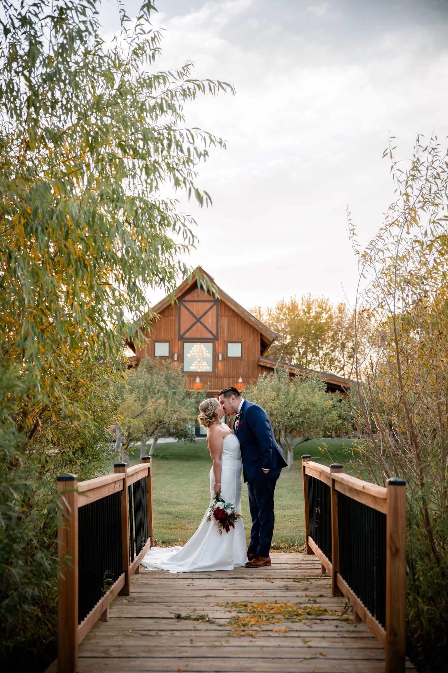 Romantic couple shares intimate moments on a rustic wooden bridge surrounded by autumn foliage at sunset.