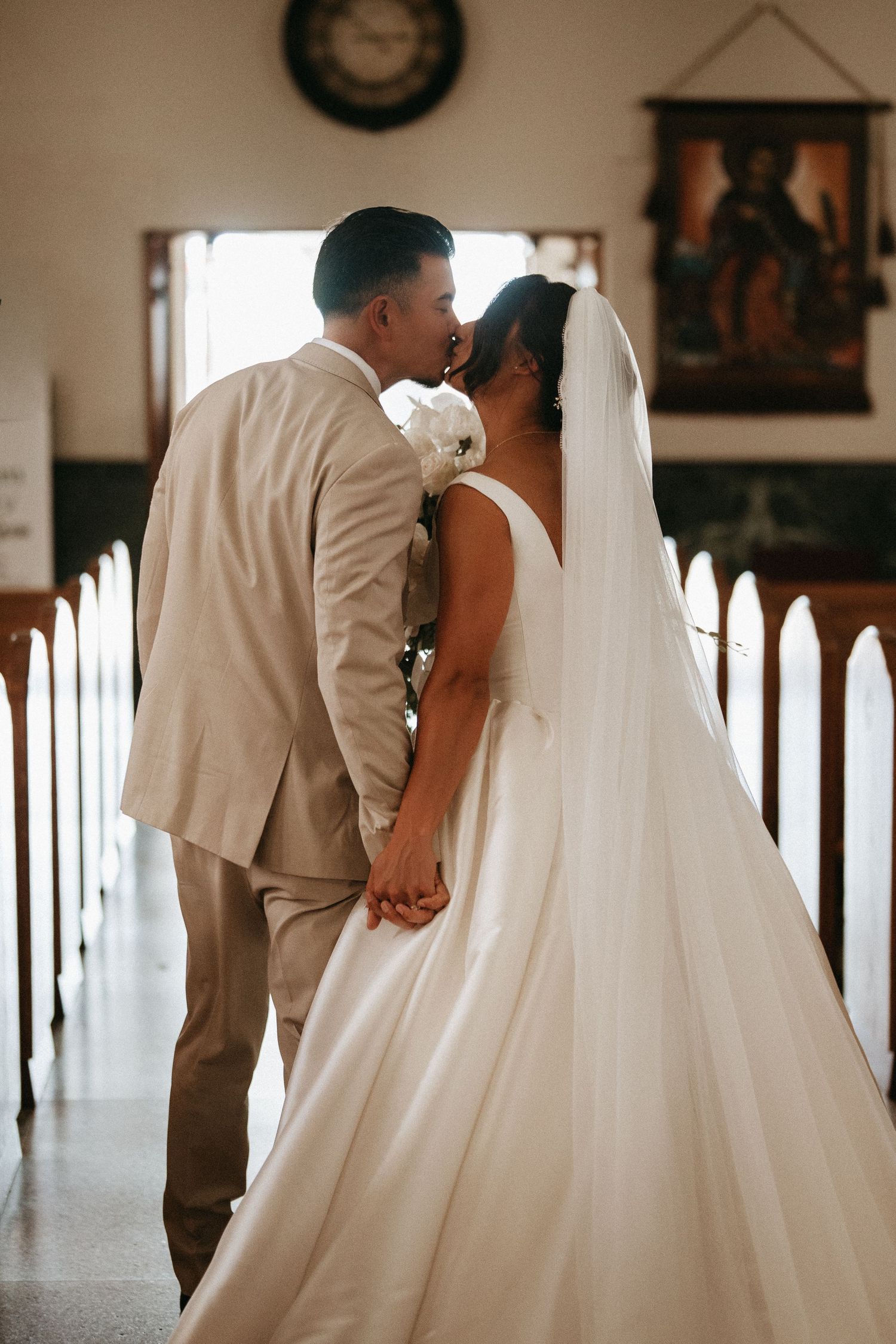 A couple shares a tender moment in a rustic venue, with the bride wearing a flowing white wedding gown.