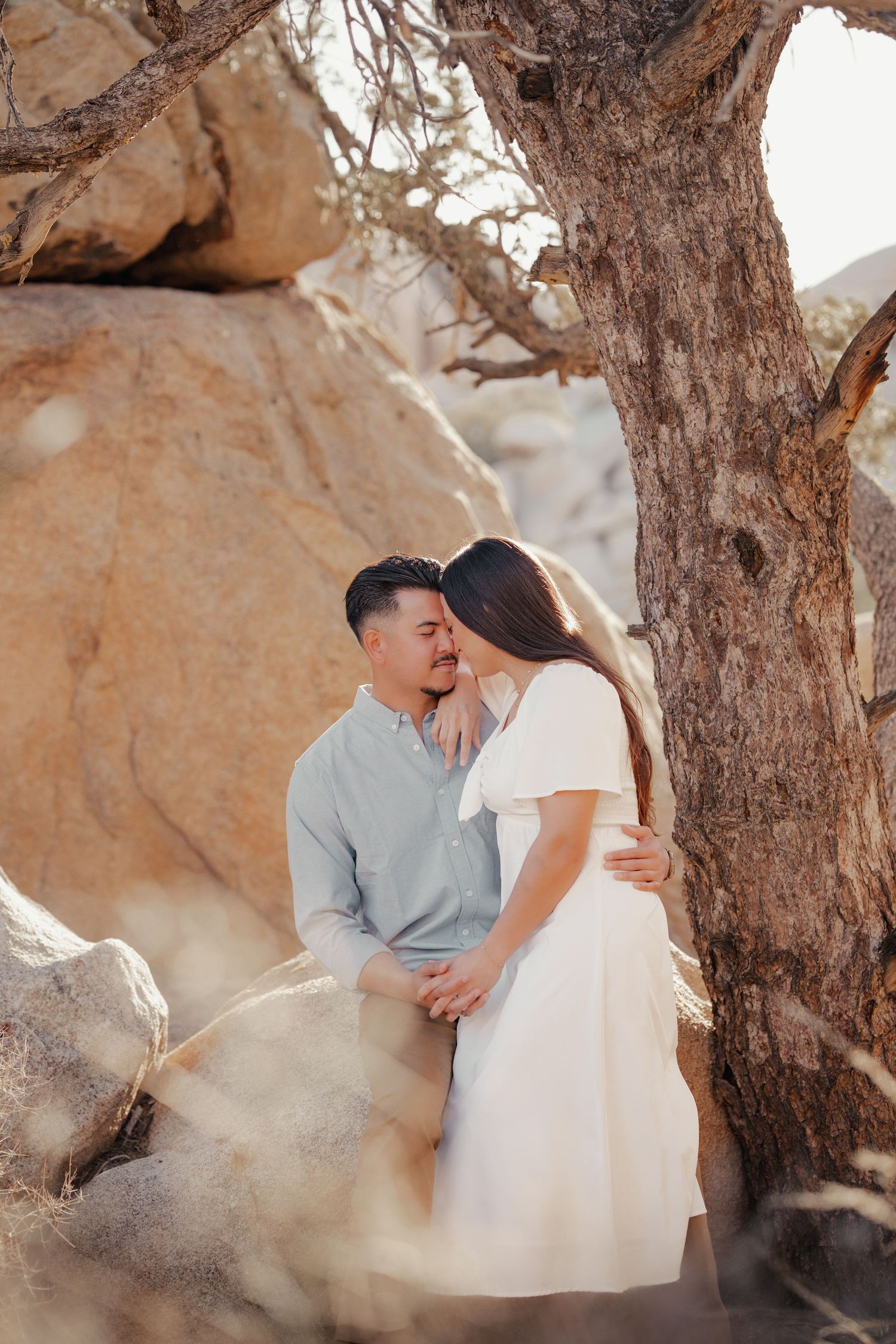 A romantic couple shares intimate moments against a rocky desert backdrop with warm lighting.